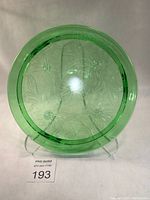 Top-down view of green uranium glass cake stand showing detailed sunflower embossed pattern and clear thick glass rim.