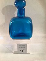 Front view of the blue glass decanter with stopper showing its shape and color.