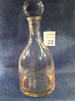 Clear lead-free crystal wine decanter with stopper in place on a dark background, showing overall shape and clarity.