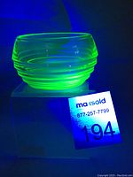 Small uranium glass bowl glowing bright green under UV light, side angle