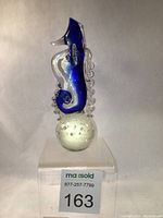 Full view of blue and clear glass seahorse paperweight on clear bubble glass base
