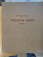 Front cover of the Historical Atlas book showing the title 'Historical Atlas of Wellington County Ontario' on a brown cloth hardcover.