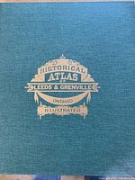 Cover of the atlas showing blue cloth binding with gold embossed lettering 'Historical Atlas of Leeds & Grenville Ontario Illustrated'.