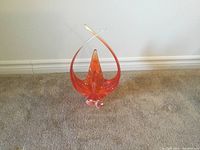 Photo of orange/red decorative glass vase 17 inches tall on carpet against white wall