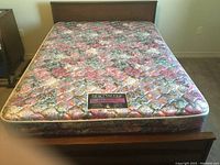 Queen size mattress with floral quilted fabric cover and BeautySleep label on bed frame.