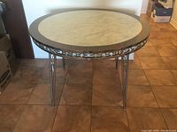 Full view of the round retro kitchen table showing metal legs, wood trim, and marble-effect tabletop.