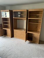 Full view of the oak veneer wall unit against a wall, showing three distinct sections with shelves, drawers, and cupboards.