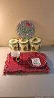 Overview photo showing all items on display: 4 red/black plaid placemats, belt mug, Santa cookie plate, Believe sign, and 3 Spode boxes grouped.