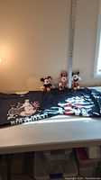 Two plastic Disney figurines (Mickey and Minnie) and two Disney-themed T-shirts laid on a table.