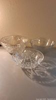 Three clear glass bowls of varying sizes and patterns shown on a surface with neutral background.