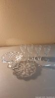 Four medium fluted stem glasses and three mini shot glasses displayed with one pedestal candy dish on table.