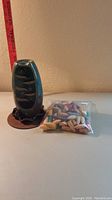 Photo showing ceramic incense burner with carved indentations and glossy blue-green glaze next to sealed plastic bag of multicolored incense cones.