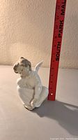 Front view of the Lladro cherub angel figurine next to a ruler showing height around 6 inches