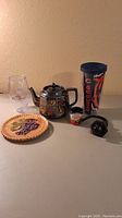 Full lot display with all items on a table against a neutral wall: grape plate, NFL tumbler, shot glass, teapot, and hold back knob.