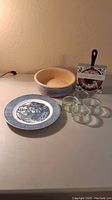 Photo of the full lot showing all items: donut mix skillet with its packaging, four small clear glass dessert cups, the ceramic southwest planter, and the Currier & Ives plate with blue and white design.