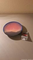 Pottery round plate with sunset gradient design and mountain silhouette, accompanied by a descriptive card.