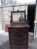 Front view of the antique oak highboy dresser with ornate mirror. Shows multiple drawers, some missing hardware, and dust accumulation.