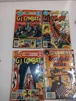 Four war comic books: three G.I. Combat issues from DC Comics and one Battlefield Action from Charlton Comics, displayed flat against a white background.