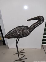 Full side profile view of the wire crane sculpture showing its long neck and detailed wire mesh body.