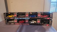Two photo angles of the full Exotic Car Collection boxed set with all eight die-cast cars visible in their windowed packaging showing the colors and models.
