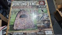 Front view of boxed Buffalo hunting tent showing umbrella style quick open design and camouflage pattern details