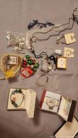 Top-down view of assorted jewelry items laid out on a surface, showing various bracelets, earrings, and necklaces including a holiday-themed bracelet and retail packaging.
