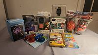Wide shot of the full lot showing various toys, smart watches, arts and crafts, and electronic items arranged on a flat surface.