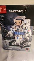 Front of box image showing astronaut figure on moon with 'Power Brick' branding and product name.