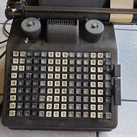 Close up photo showing the top half of the adding machine keyboard with numbered keys labeled by months and the two round dials.