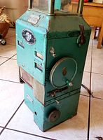 Front and side view of antique metal bus coin/token collector showing levers, number plate, and metal body with teal paint.