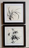 Two square framed Chinese ink wash paintings of orchids and bamboo, black wood frames, approximately 13.5" x 13.5" each.