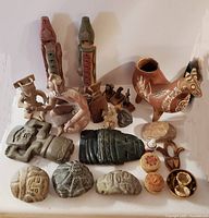 Lot of 27 pieces including ceramic and carved stone sculptures with intricate carvings and animal forms, along with small woven baskets, beaded items, and a ceramic animal vessel. Tallest sculpture approx. 10.5 inches.
