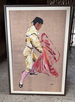 Full view of Midcentury Modern style painting of a bullfighter holding a red cape, framed in brown wood.