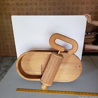 Front and top angle of carved wooden sardine can sculpture with attached roller and handle, showing detailed craftsmanship and wood grain.