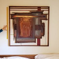 Full frontal view of the framed art piece mounted on wall with measuring stick alongside.