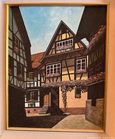 Close up of oil painting showing detailed German half-timber architecture with flower boxes and blue sky.