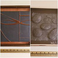 Two framed art pieces side by side with measuring tape below showing approximately 10 inches width each. One shows textured beach rock relief signed 1982, the other a geometric abstract art piece.