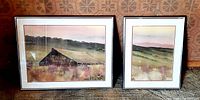 Two framed watercolor paintings placed side by side, one of a barn and the other a landscape, both with silver tone metal frames.