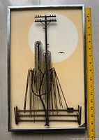 Front view of the midcentury modern metal artwork in silver tone frame with measuring tape showing size approximately 16.25 x 10.5 inches.