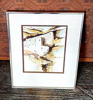 Overall image showing framed watercolor artwork with cliff dwellings motif in earth tones, set against a patterned background.