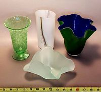 Four art glass vases and decor pieces shown in one image with measuring tape in foreground to show size.