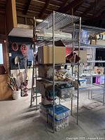 Full view of metal shelving unit loaded with various boxes and containers, some shelves appear detached.