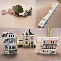 Multiple painted wooden and metal houses including a white cityscape base with multiple white buildings, three detailed Victorian houses, and a connected set of small houses with a green tree.