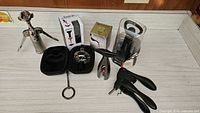 Photo shows various bar tools including corkscrews, wine aerators in cases, a metal handled acrylic wine rack, and boxed champagne bottle opener all arranged on a white surface against a wood backing.