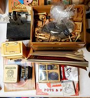 Overview of assorted kitchen-themed miniatures in cardboard and plastic packaging, including wooden furniture, metal stove, and vintage style miniature boxes.
