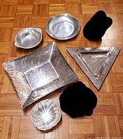 Five metal decor and serving plates displayed together on wood floor