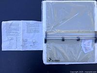 Photo showing the adjustable standing desk platform wrapped in plastic and the included instruction sheet.