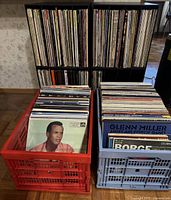 Red and blue crates filled with vinyl records in front of a shelving unit