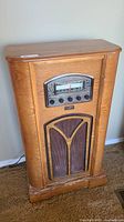 Front view of the 1944 Crosley Thomas floor radio showing wooden cabinet, radio dial, tuning knobs, and speaker grille.
