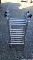 Top view of folded articulating aluminum ladder, showing rungs and black locking knobs on each articulated joint.